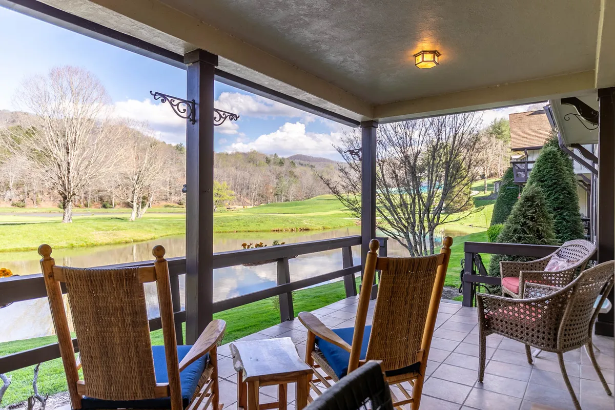 This exterior image features a pair of classic rocking chairs positioned to overlook a tranquil pond, framed by trees and a sweeping view of a golf course. The setting exudes peace and invites guests to relax, enjoy nature, and take in the surrounding landscape, aligning with the family-friendly and explorative spirit of the section.