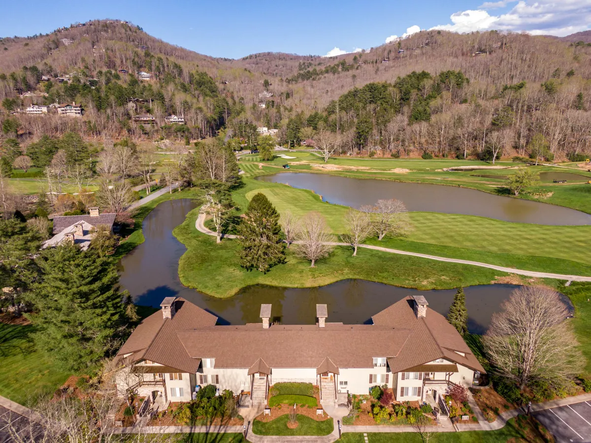A sweeping view of a lush green golf course beside a tranquil pond, with surrounding mountains and well-maintained landscaping. The area is ideal for leisurely walks, picnics, and wildlife observation.