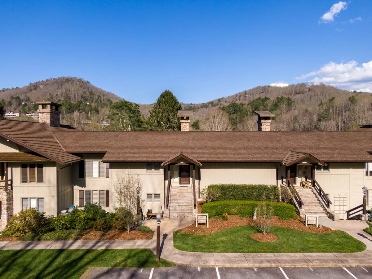 An inviting view of a two-story building set against a landscaped yard and dramatic mountain backdrop. The scene suggests community gatherings, outdoor relaxation, and the appeal of a mountain town atmosphere.