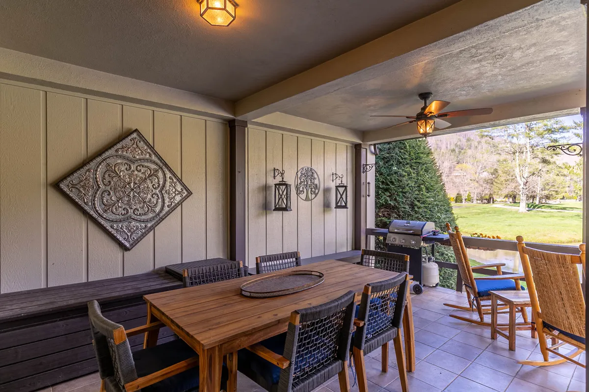 A dining area with a large table sits adjacent to windows that showcase serene outdoor views. Decorative wall art adds charm, and the space invites gatherings for meals or morning coffee while taking in the scenery.
